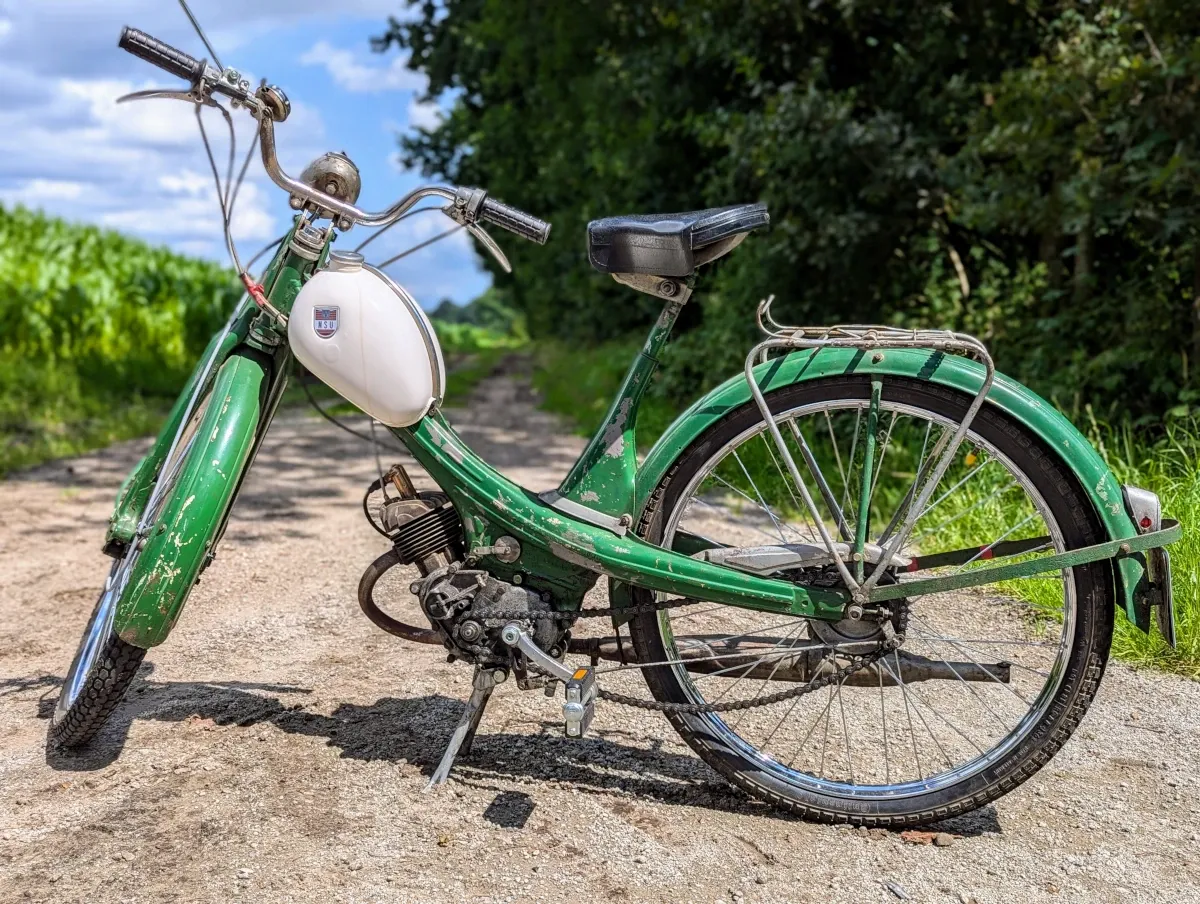 An NSU Quickly moped in green standing on a country lane